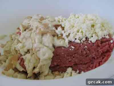 Adding bread and feta to meat for greek recipe keftedes kalokairinoi summer meatballs.