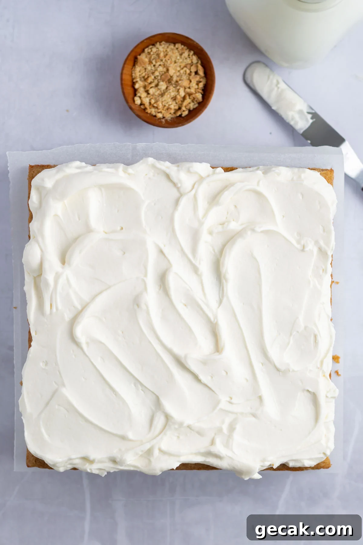No-Bake Graham Cracker Cake Recipe: Layered Dessert with Creamy Filling 12 frosting topping swirled on top of cake with a bowl of graham cracker crumbs