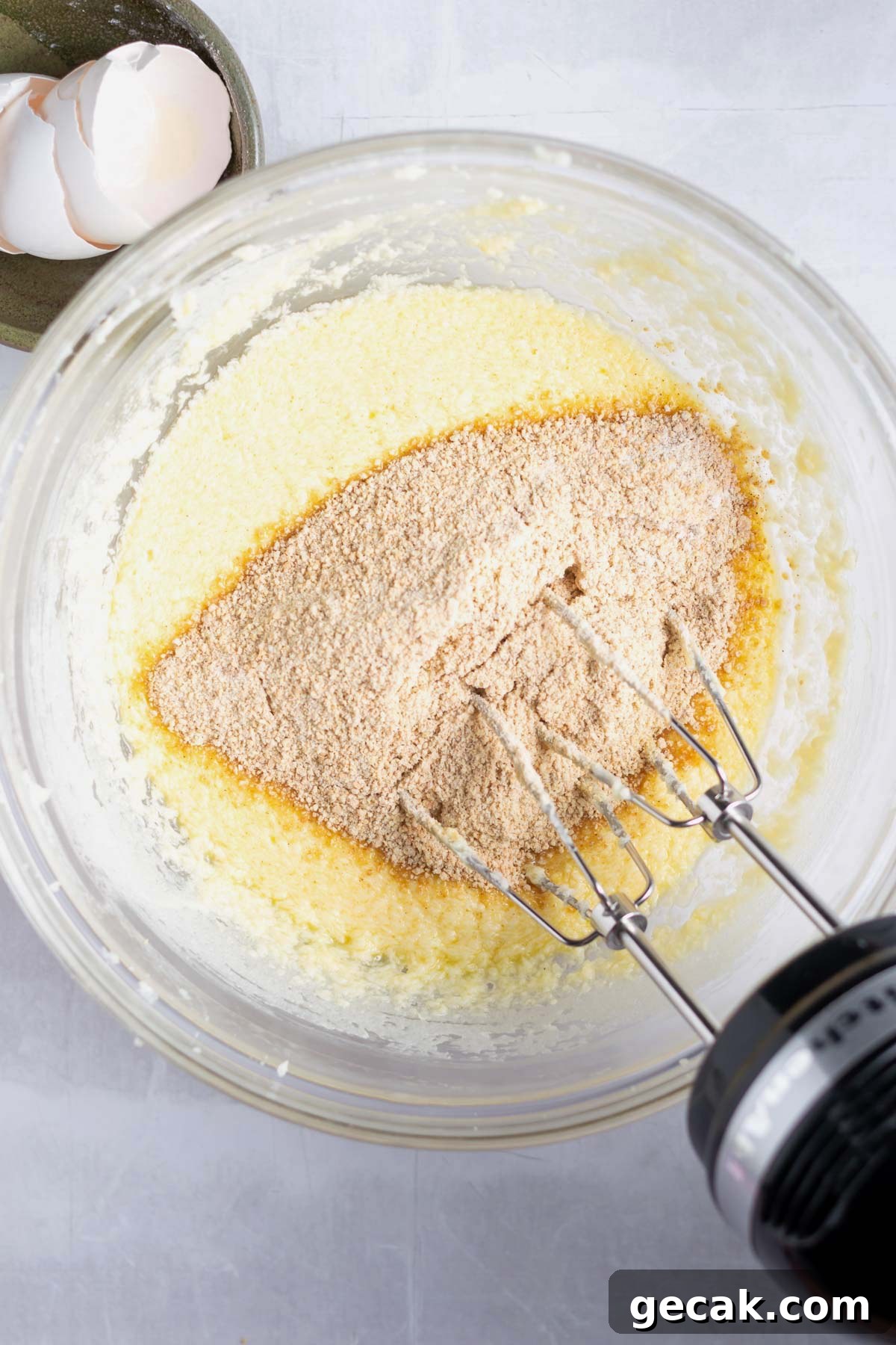 No-Bake Graham Cracker Cake Recipe: Layered Dessert with Creamy Filling 8 dry ingredients being added to wet ingredients in a bowl with a hand mixer