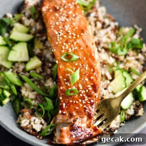 A fork in a fillet of salmon topped with sweet chili sauce.
