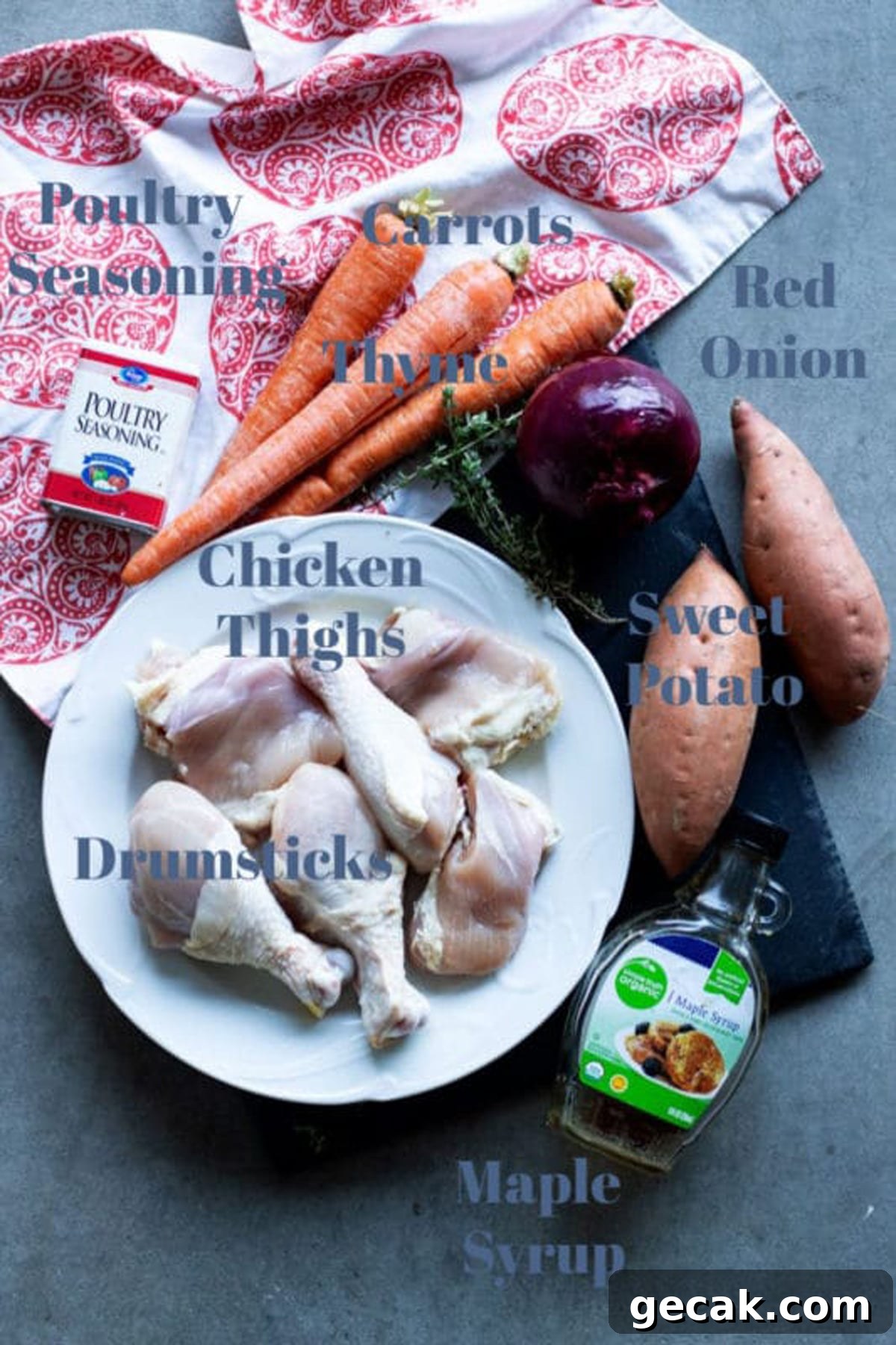 Chicken thighs and drumsticks, carrots, red onion, sweet potato, thyme, maple syrup, seasoning on table.