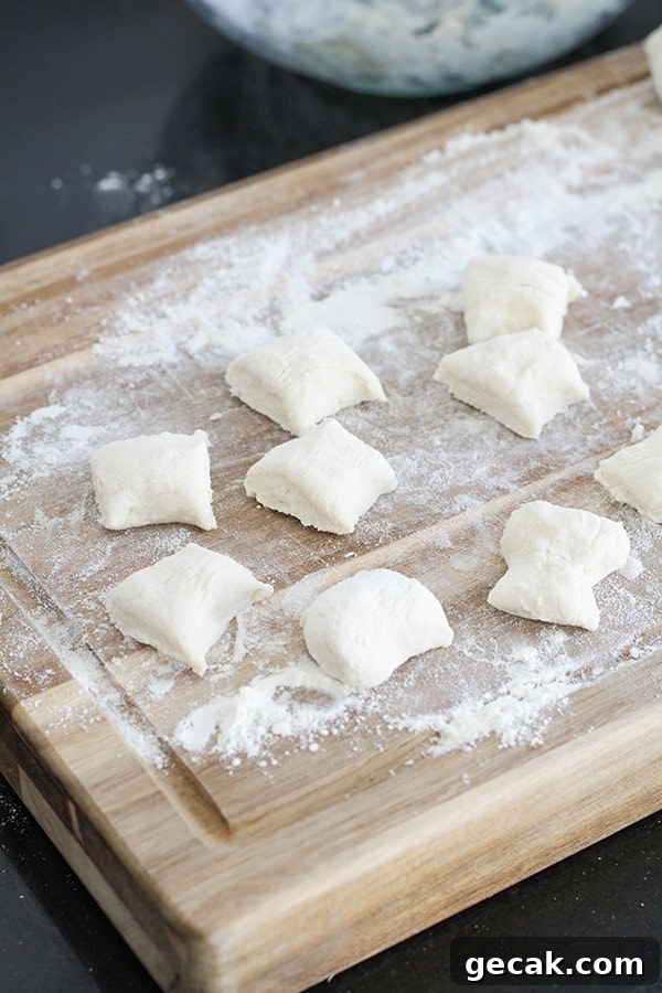 dough cut into bite-sized pieces on a wooden cutting board.