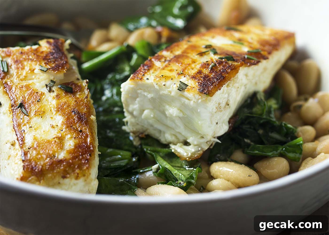 Close up of a piece of halibut showing the seared outside and juicy inside.