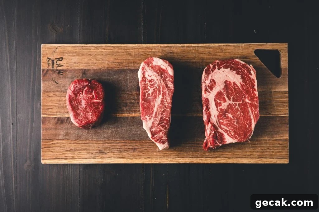 Three steaks on a wooden cutting board.