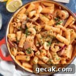 Creamy chorizo and prawn pasta in a red pan.