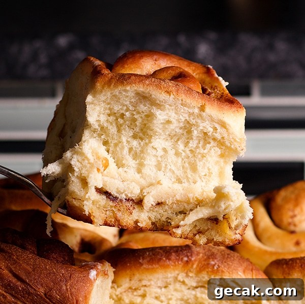 Lifting a freshly baked, homemade cinnamon roll from the pan.
