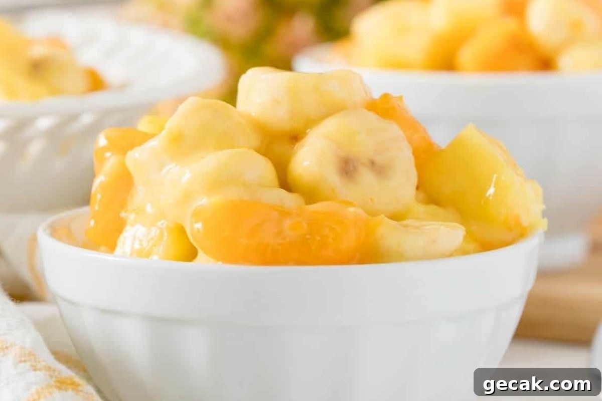 A bowl of mango and pineapple jello salads with a spoon.