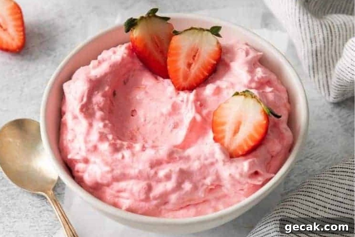 Strawberry jello salads in a bowl with a spoon.