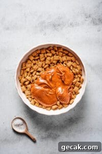 Chocolate Peanut Butter Muddy Buddies Snack Mix Recipe 4 A large mixing bowl of Chex cereal, with a melted peanut butter chocolate mixture poured on top.