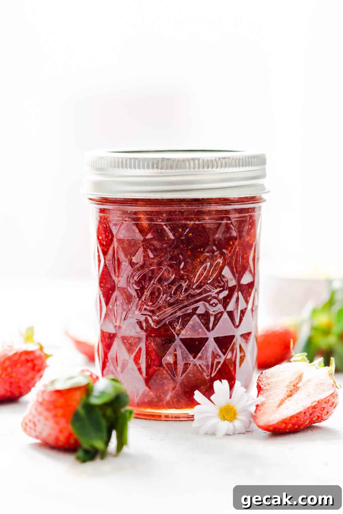 Homemade Strawberry Jam Recipe: Small-Batch Method for Fresh Flavor 11 straight ahead shot at a jar with strawberry jam and some strawberries around it