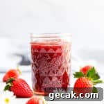 straight ahead angle shot of a jar with strawberry jam and fresh strawberries on side