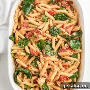 Cheesy Baked Penne Pasta with Crispy Breadcrumb Topping 9 Pasta is stirred with baby spinach in a white baking dish.