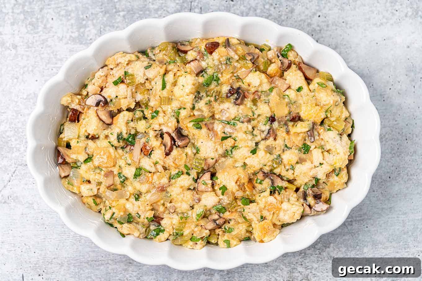 Classic Old-Fashioned Bread Stuffing Recipe for Thanksgiving 6 An oval white casserole of old fashioned bread stuffing ready to be baked.