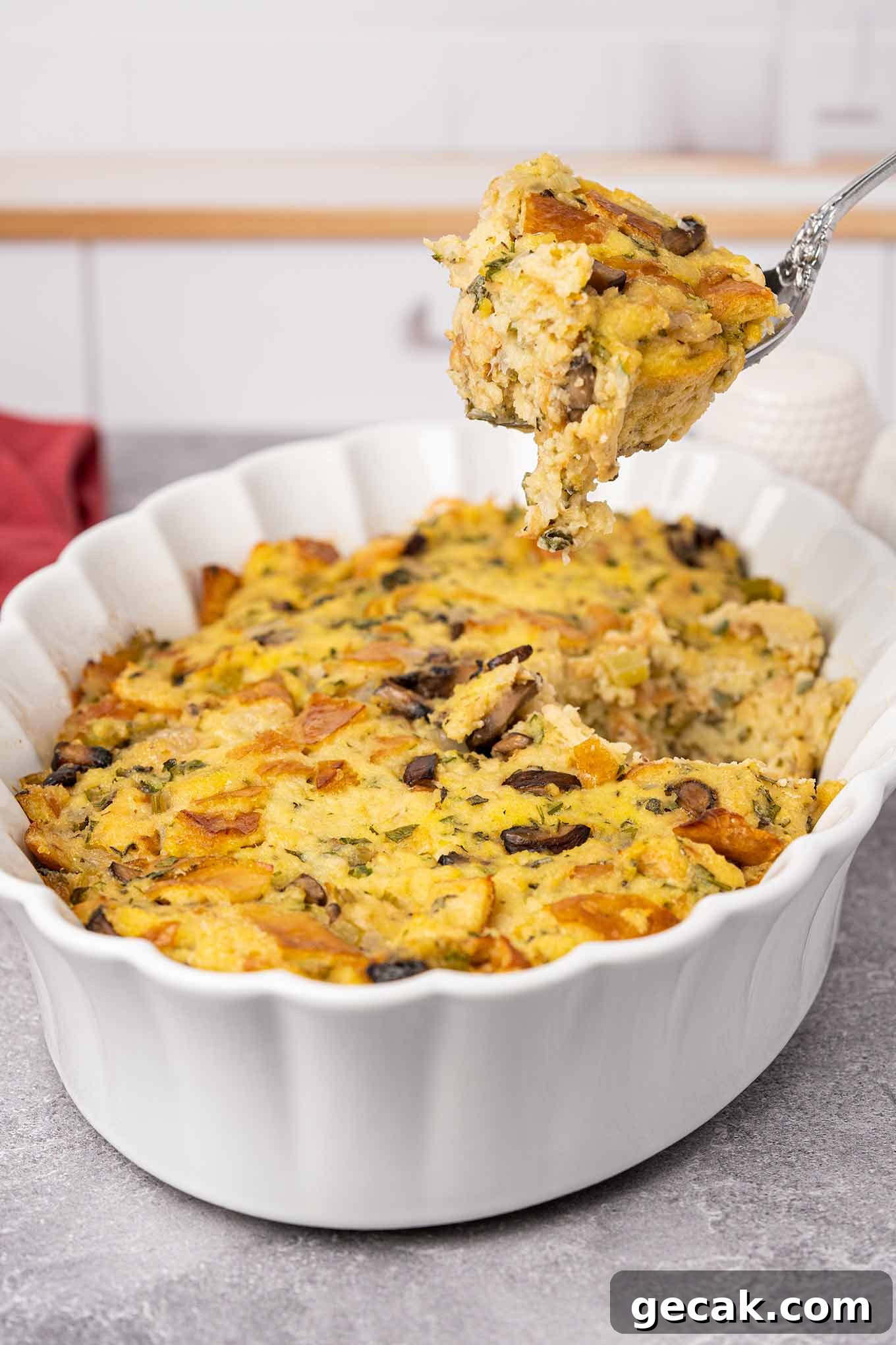 Classic Old-Fashioned Bread Stuffing Recipe for Thanksgiving 7 A casserole of traditional bread stuffing with a spoonful being removed for serving showing its moist, fluffy texture.