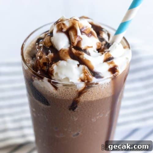 chocolate slushy recipe close up in a glass with whipped cream, chocolate syrup, and a straw from the side