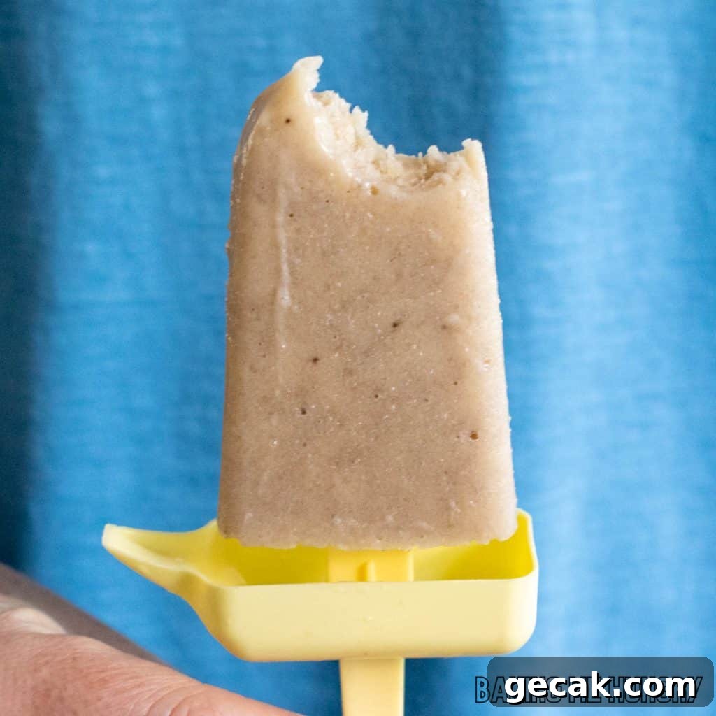 one of the creamy banana popsicles held up missing a bite