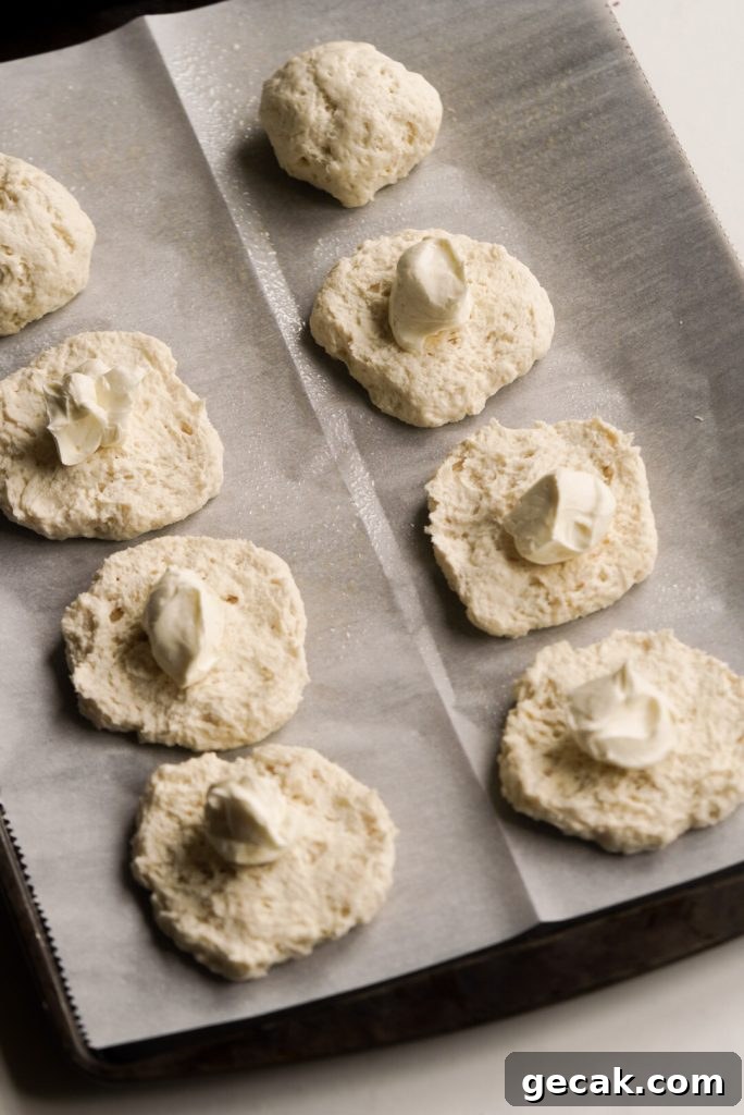 bagel bite dough circles on a baking sheet with cream cheese on top of them