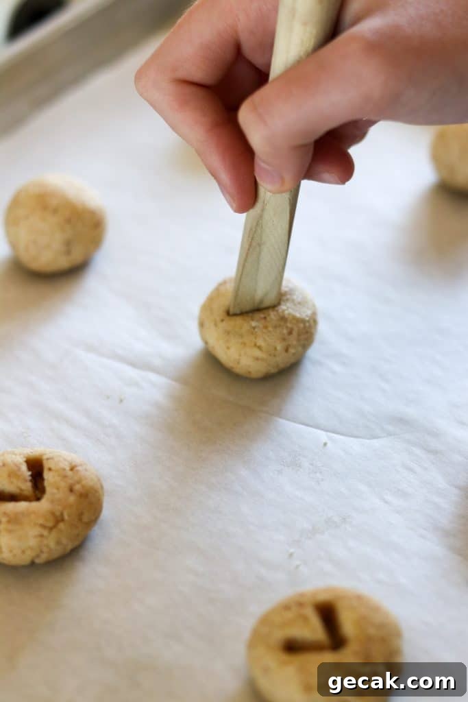 Raspberry Hazelnut Heart Cookies Recipe 6 A person making a v shape in a round of cookie dough