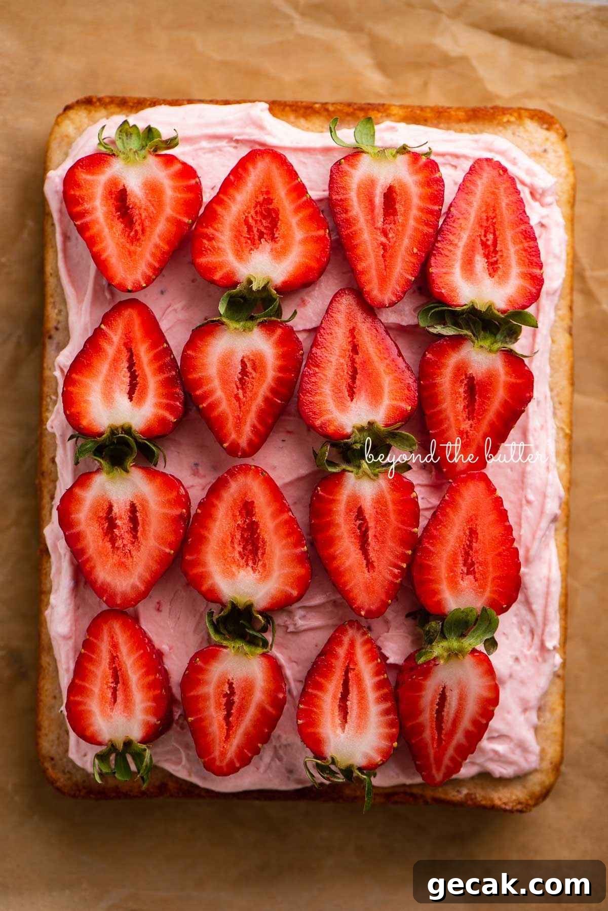 Mini strawberry sheet cake topped with strawberry buttercream frosting on parchment paper.