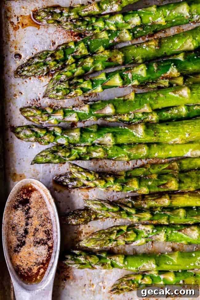 roasted asparagus on a baking sheet with a ramekin of browned butter.