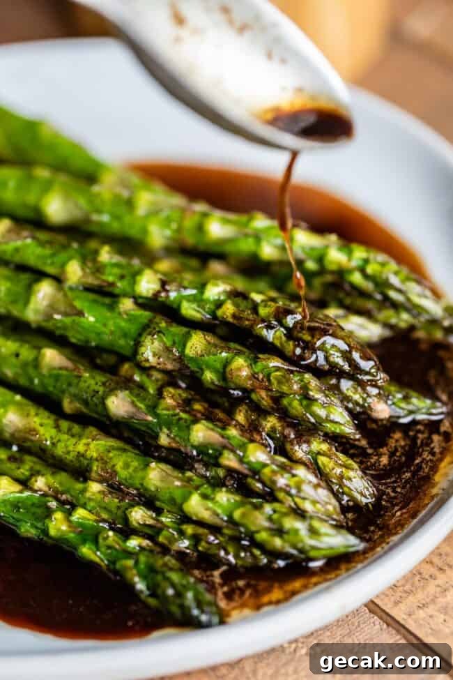 roasted asparagus with browned balsamic butter being drizzled from a spoon.