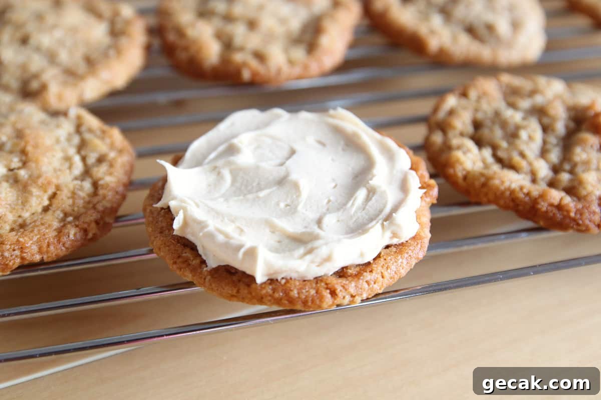 An oatmeal cookie on a wire rack with some buttercream frosting spread on top.