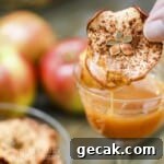 Side close up shot of a hand dipping a cinnamon apple chip into a glass with caramel
