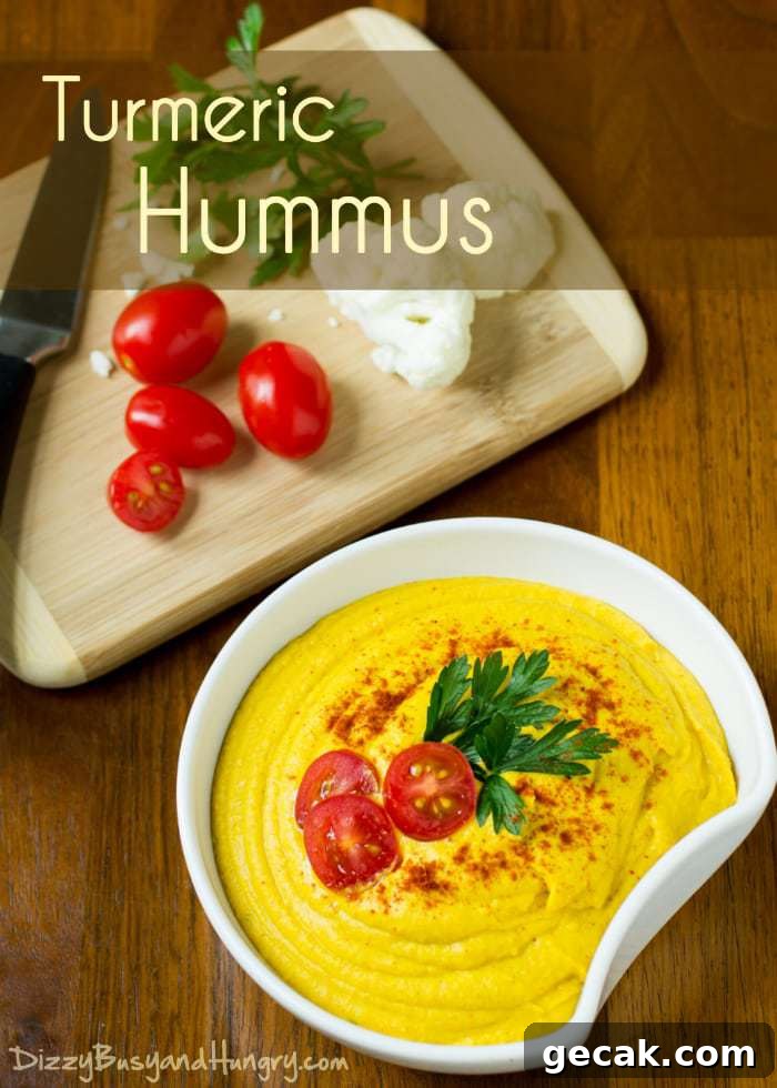 Turmeric hummus sprinkled with herbs and sliced tomatoes