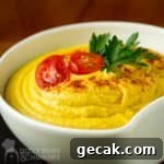Close up side shot of hummus garnished with halved cherry tomatoes