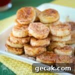 Pan fried banana snacks piled on a white square dish and placed on yellow and green napkins.