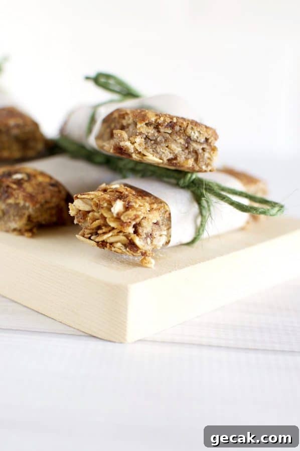 Three muesli bars stacked on a wooden cutting board. 