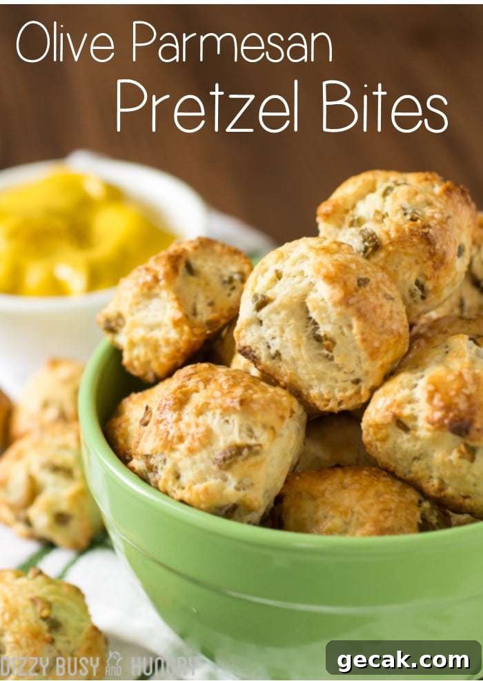 Side view of olive parmesan pretzel bites stacked in a green bowl with lemons in the background. 