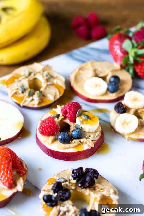 angle view of apple slices topped with fruits, peanut butter and nuts - after school snacks