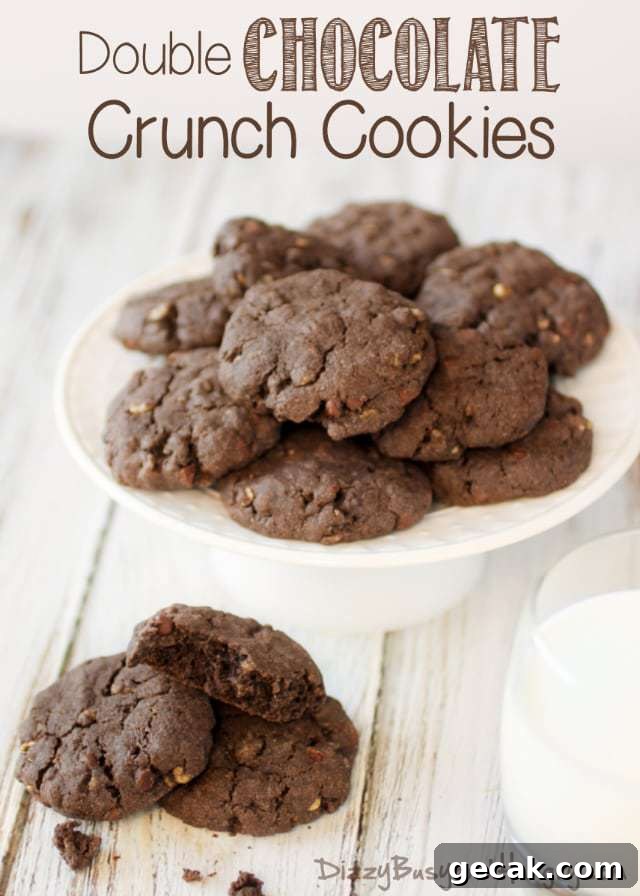 Side view of double chocolate crunch cookies layered on a white elevated plate on a white wooden table. 
