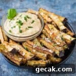Side angled shot of eggplant fries garnished with basil and parmesan on a black plate