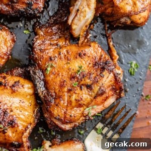 smoked chicken thighs on a plate with a fork and fresh herbs.