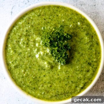 Parsley and Walnut Pesto Recipe: Fresh Homemade Sauce 7 Bright green parsley pesto in a white bowl, garnished with a sprig of fresh parsley.
