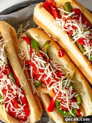 Three sausage and peppers sandwiches topped with marinara and cheese.