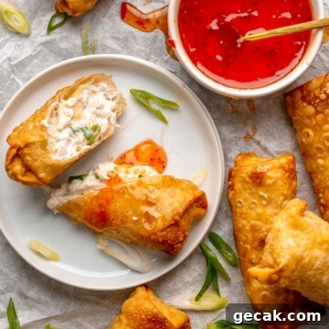 Crab rangoon egg rolls on a platter with dipping sauce.