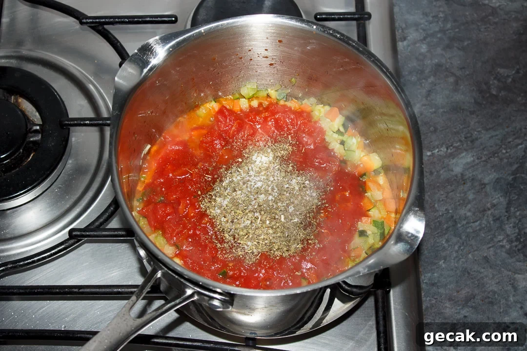 Vegetables, tinned tomatoes and herbs cooking in a large saucepan