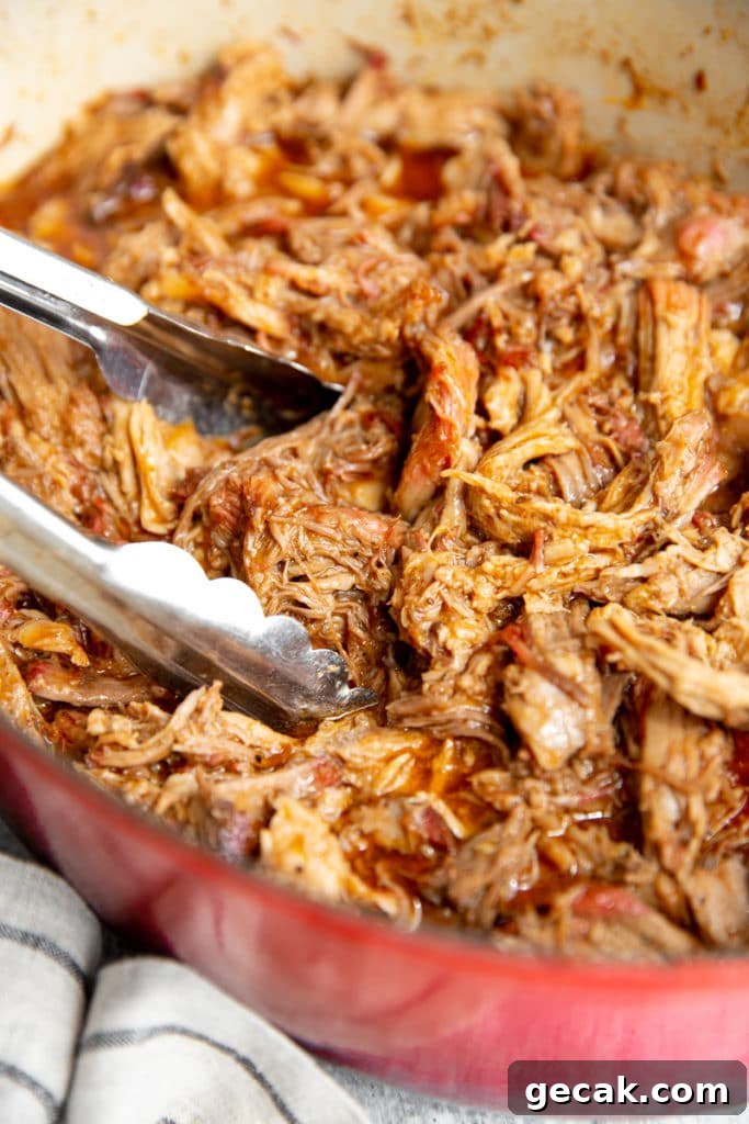 Close up of Traeger pulled pork in a pot with tongs.