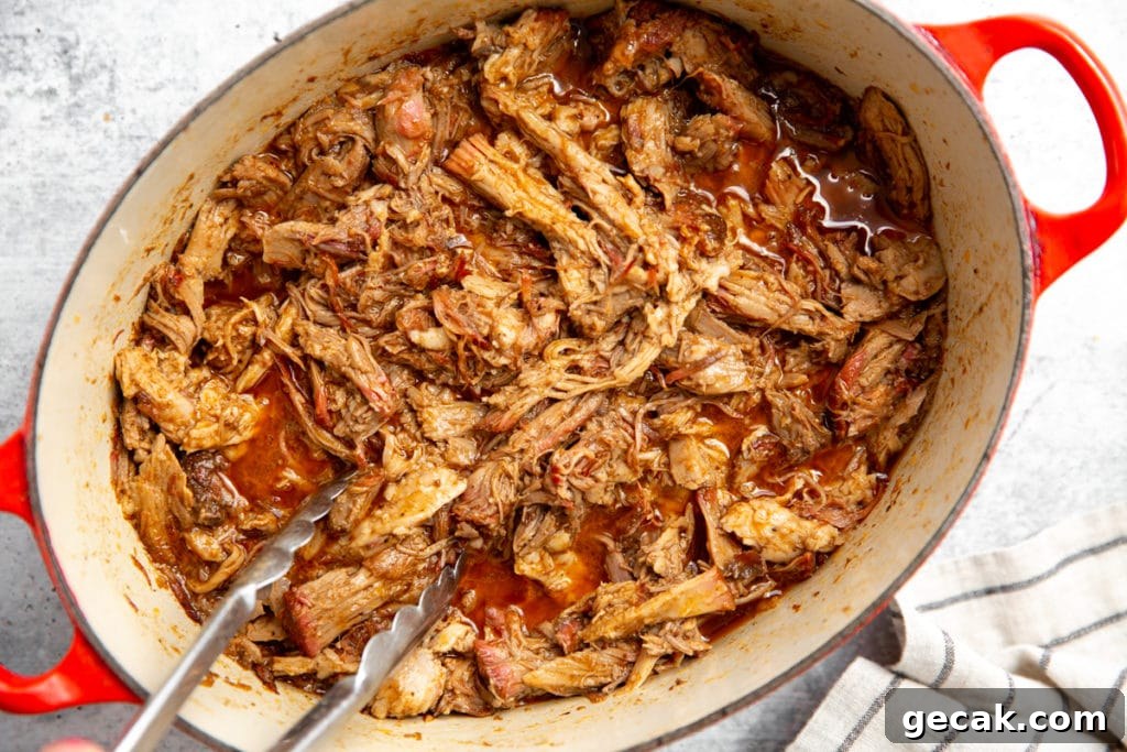 Barbecue pulled pork in a pot with tongs.