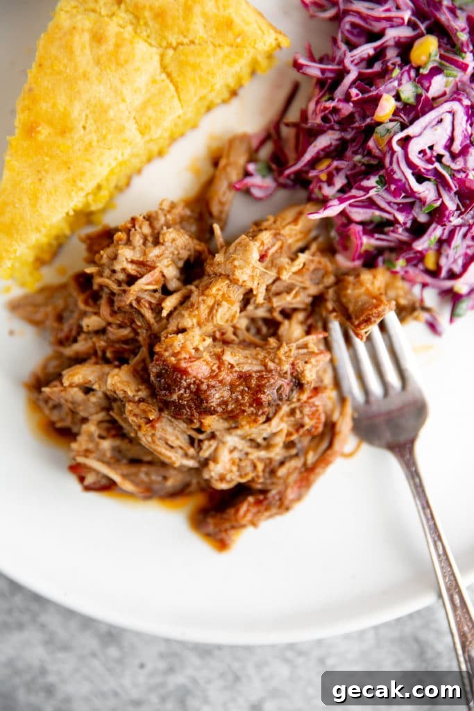 Smoked pulled pork on plate with cornbread and coleslaw alongside.