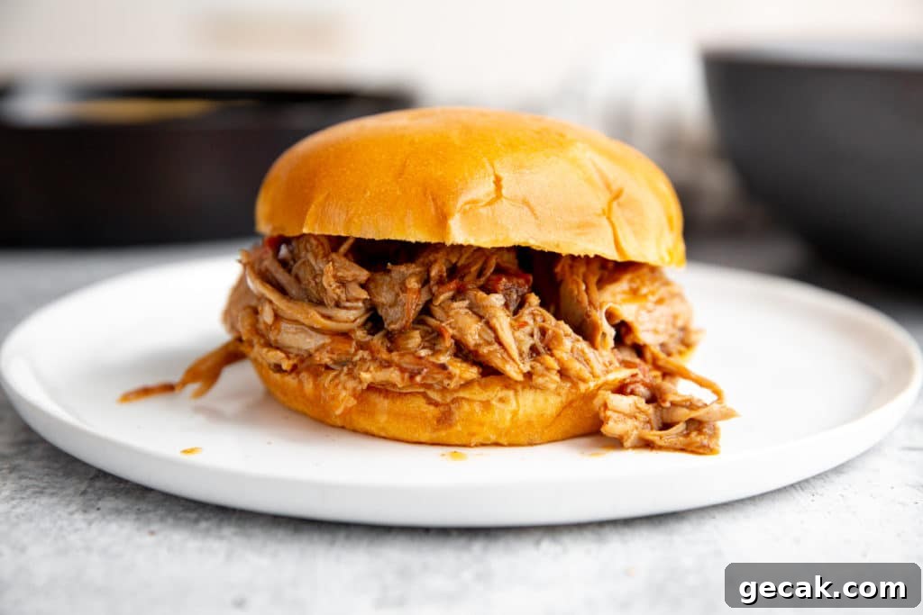 Smoked pulled pork in a bun on a plate.