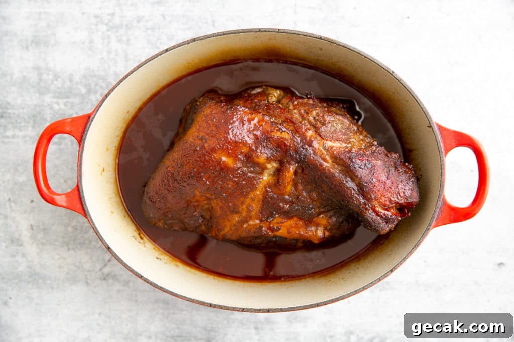 Smoked pork shoulder in Dutch oven with barbecue sauce.