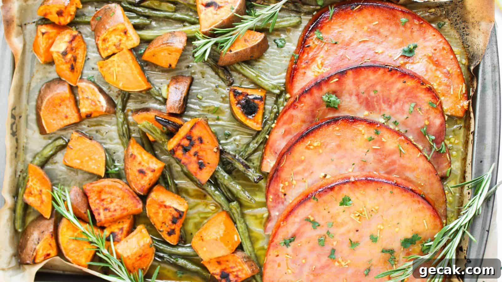 A baked dish with slices of glazed ham, roasted sweet potato cubes, and green beans, garnished with rosemary sprigs.