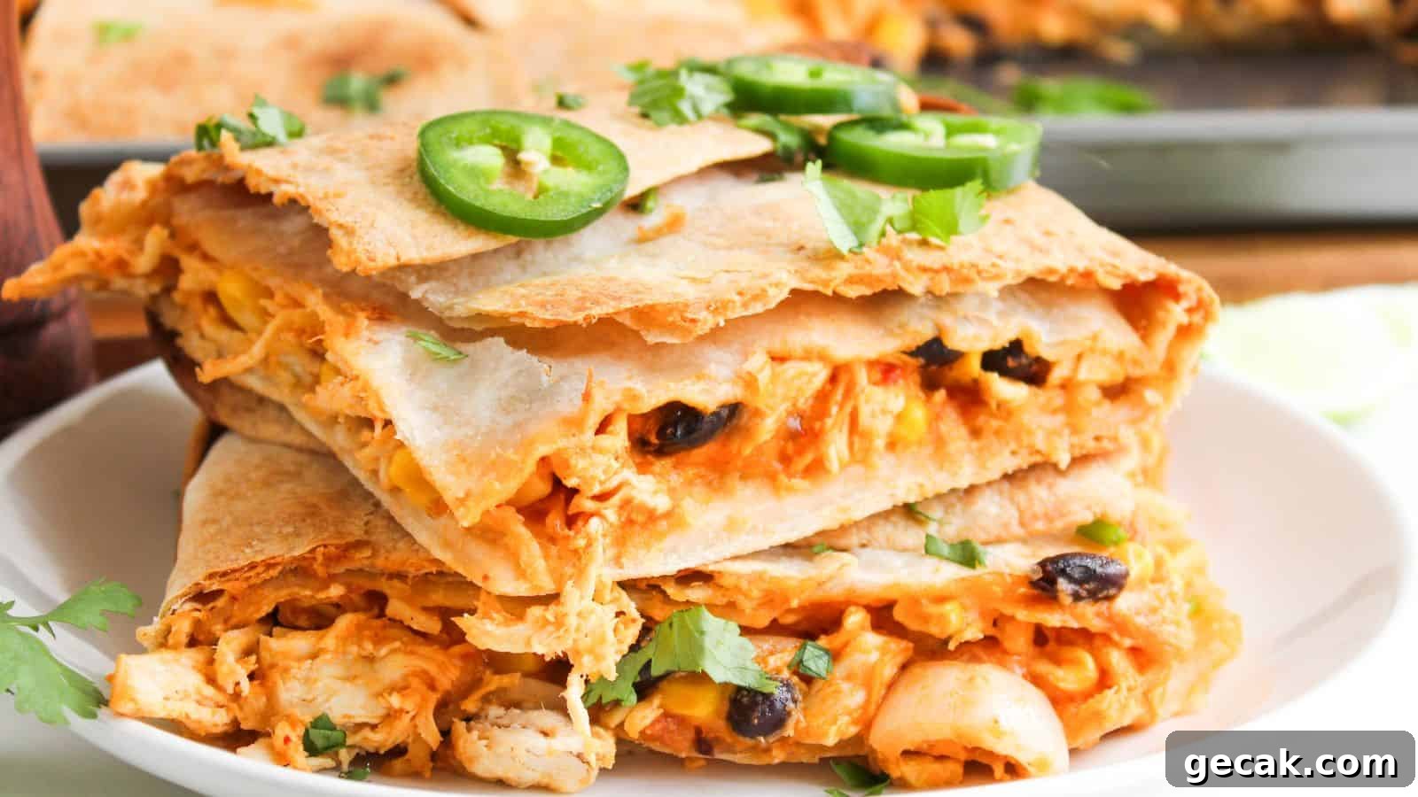 Close-up of stacked quesadilla slices filled with cheese, beans, and chicken, topped with sliced jalapeños and cilantro, on a white plate.