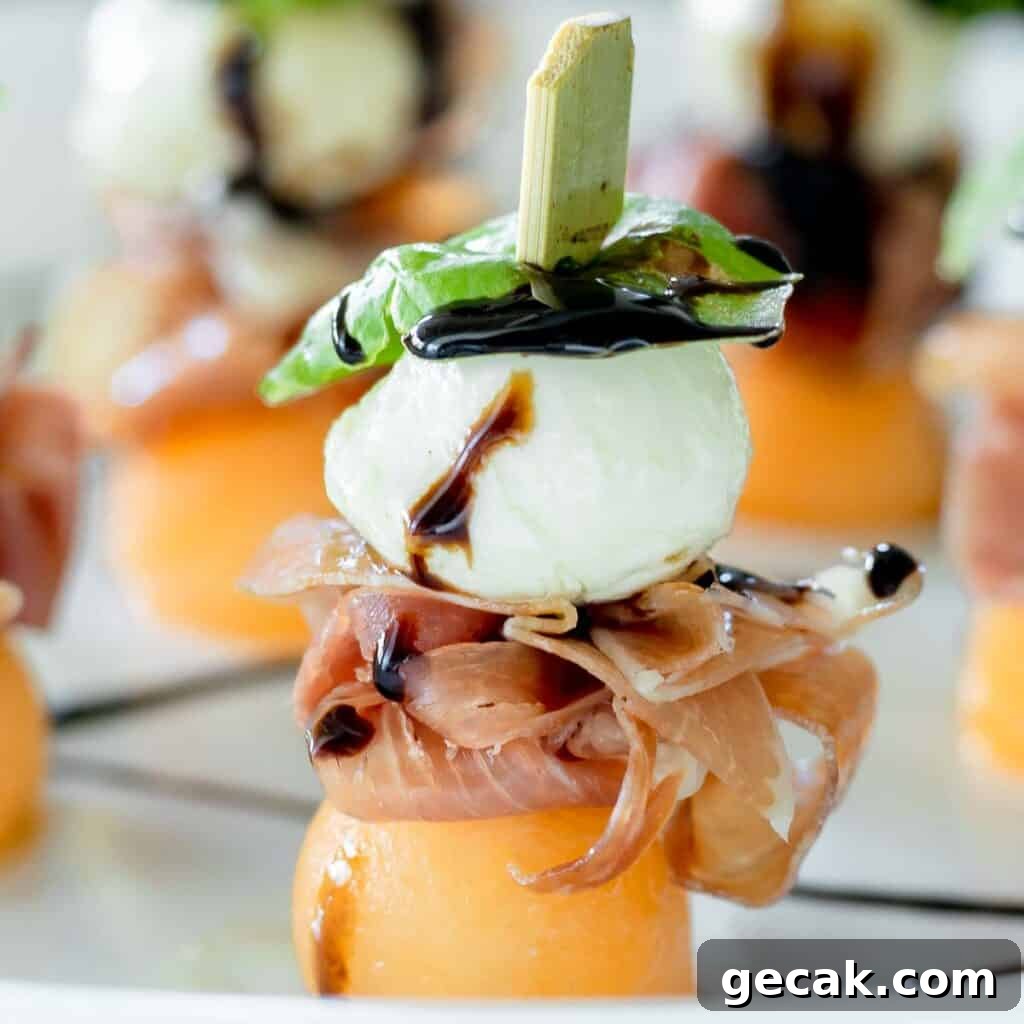Prosciutto melon mozzarella skewers on a plate drizzled with balsamic glaze.