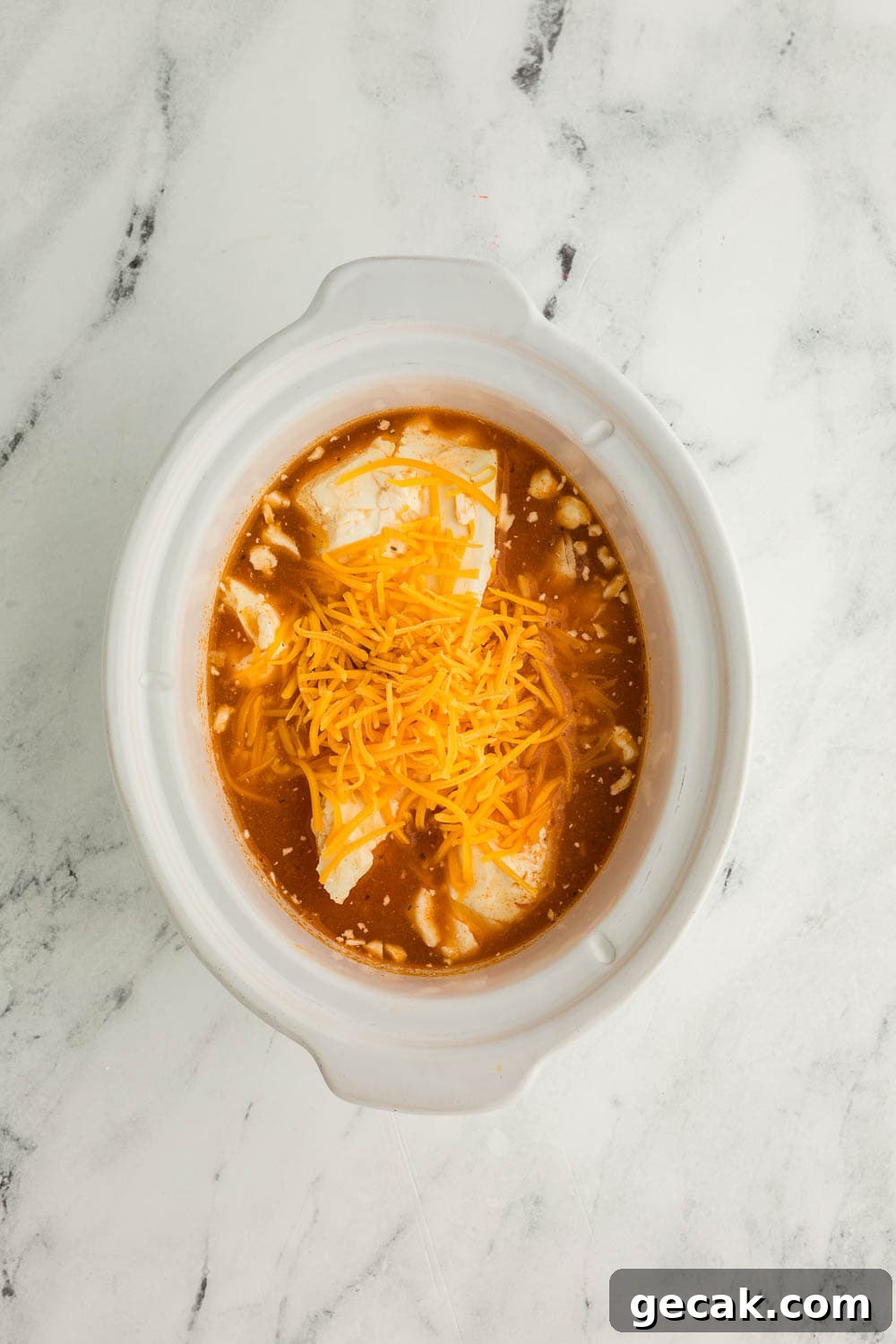 Slow Cooker Buffalo Chicken Dip: Creamy Cheesy Party Recipe 6 Chicken, buffalo sauce, cream cheese, and shredded cheese mixture in slow cooker bowl