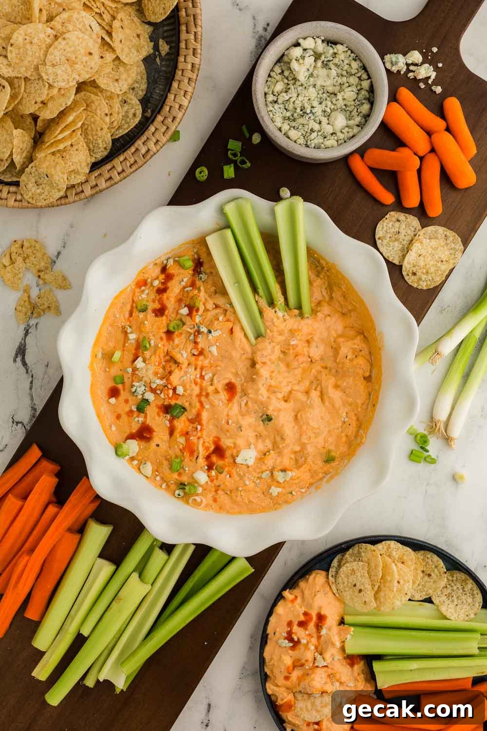 Slow Cooker Buffalo Chicken Dip: Creamy Cheesy Party Recipe 8 Cheesy Slow Cooker Buffalo Chicken Dip garnished in bowl with celery sticks inside next to celery, carrots, and tortilla chips
